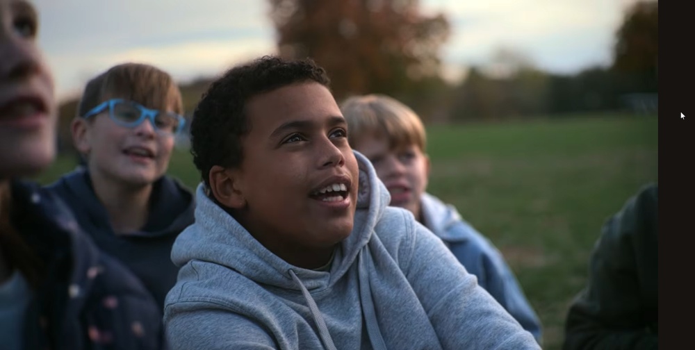 Smiling boy with friends enjoying autumn sunset in park