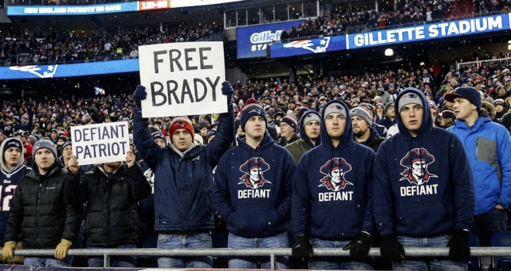 Patriots fans hold Free Brady and Defiant Patriot signs in snow