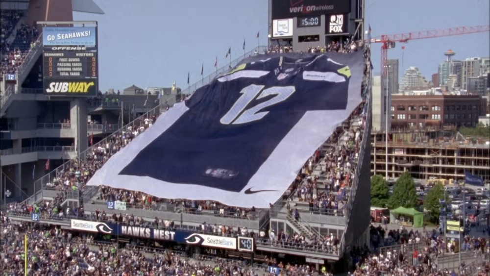 Seattle Seahawks fans unfurl giant #12 flag in Lumen Field stands.