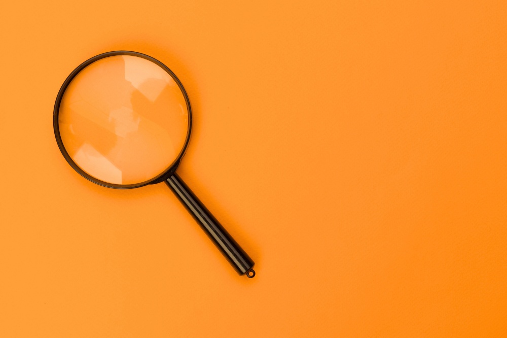 Black magnifying glass on bright orange background