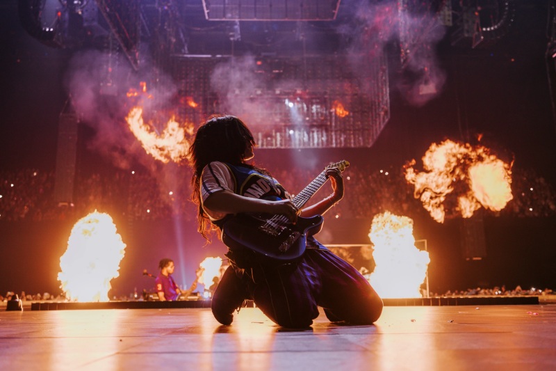 Performer on stage facing a massive crowd in a packed arena