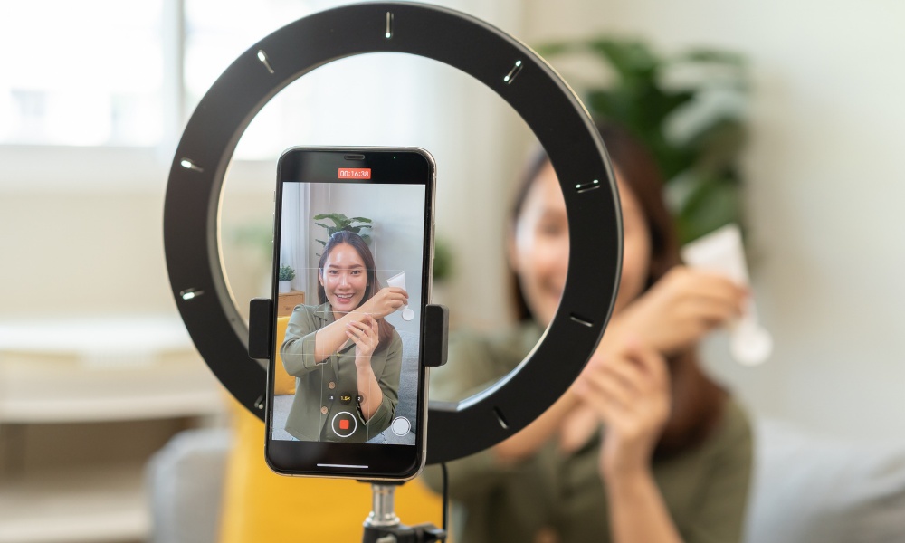 Woman filming herself with smartphone and ring light for content creation