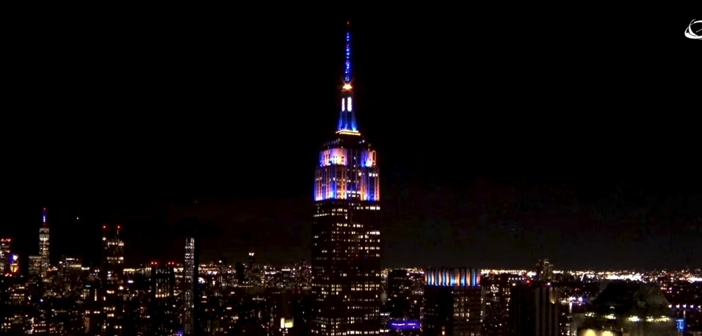 Empire State Building lit in blue and orange at night NYC