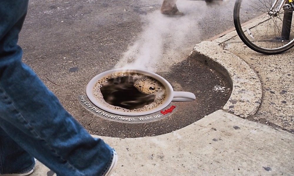 Folgers guerrilla ad steaming coffee cup painted around NYC manhole