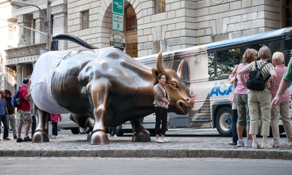 Tourists posing with Charging Bull bronze sculpture in Lower Manhattan