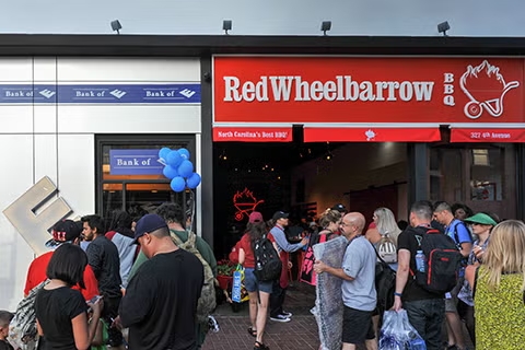 Crowd lines up outside Red Wheelbarrow BBQ storefront event