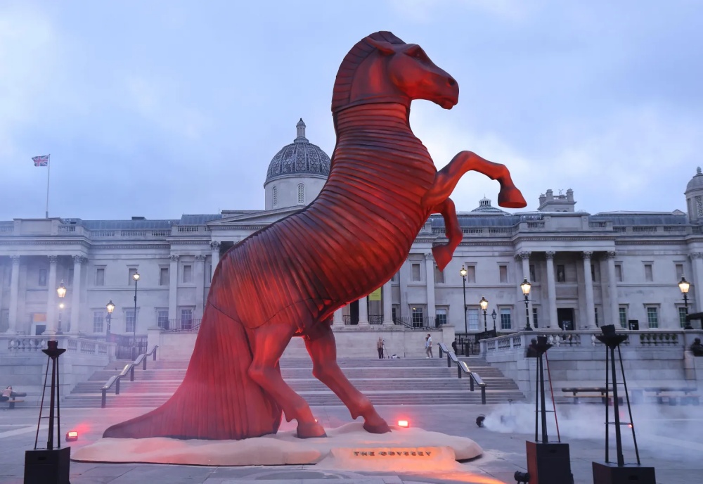 Red-lit "Odyssey" horse statue rises in London's Trafalgar Square.