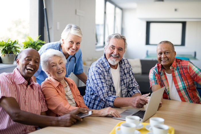 Group of elderly people sitting around table laughing.