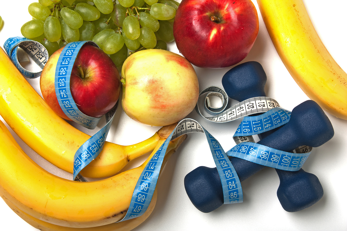 Tabletop with apples, grapes, bananas and free weights.