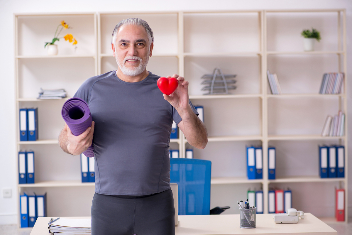 Man holding a yoga mat and a heart shaped object.