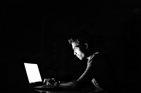 Person looking at a laptop in a dark room.