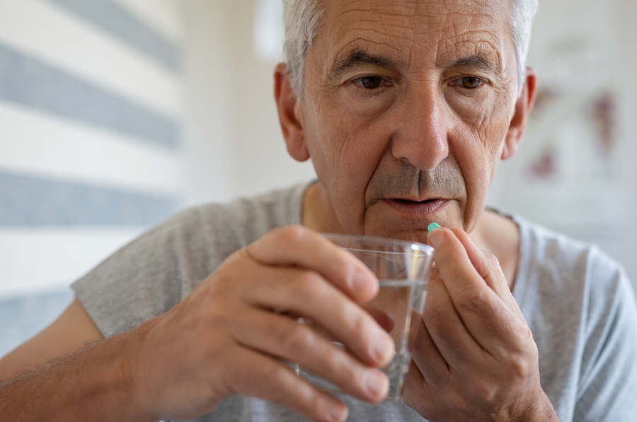 Man taking a pill with a glass of water.