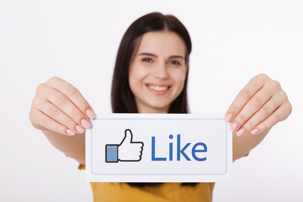 Woman holding Facebook "Like" sign as example of a critical factor in social media strategy success.