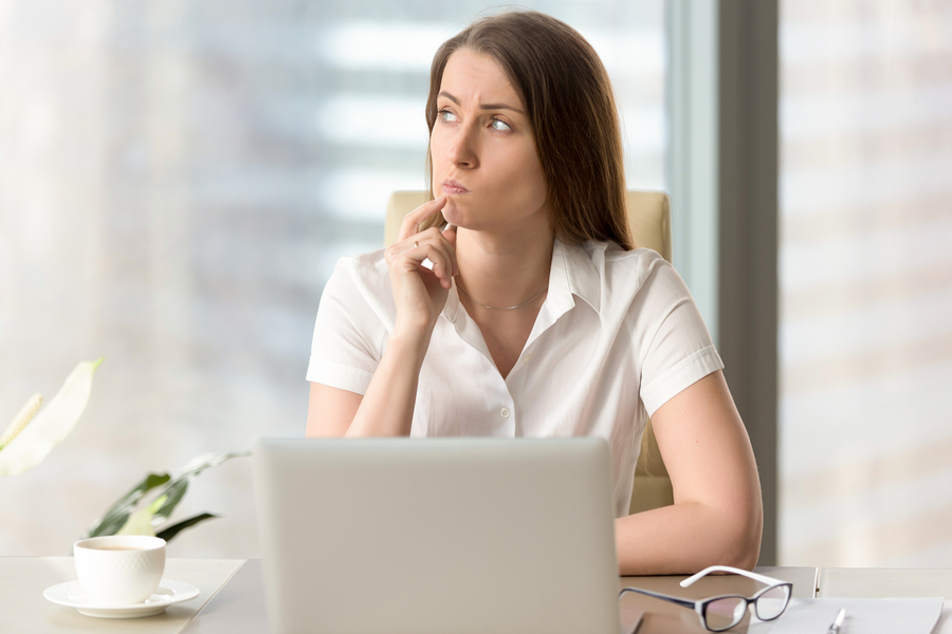 Woman sitting at her desk looking up in contemplation.