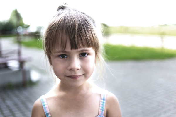 Girl with a slight smile standing outside.