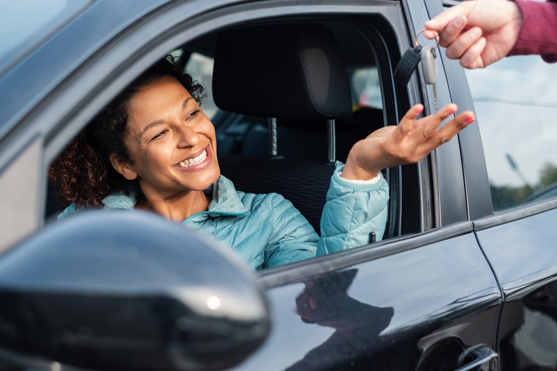 Woman reaching for keys from a car salesman.