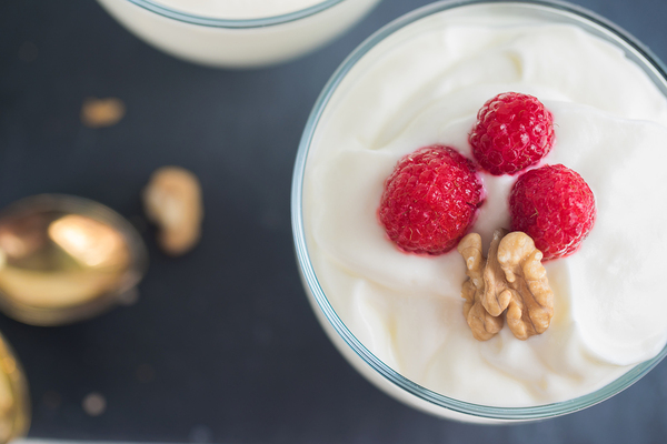 Bowl of yogurt with raspberries and walnuts.