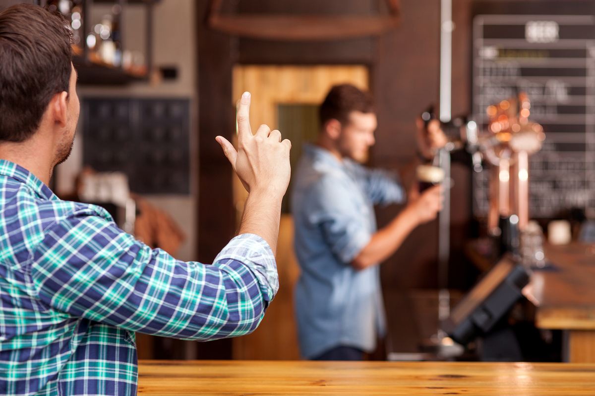 Man flagging a bartender at a pub.