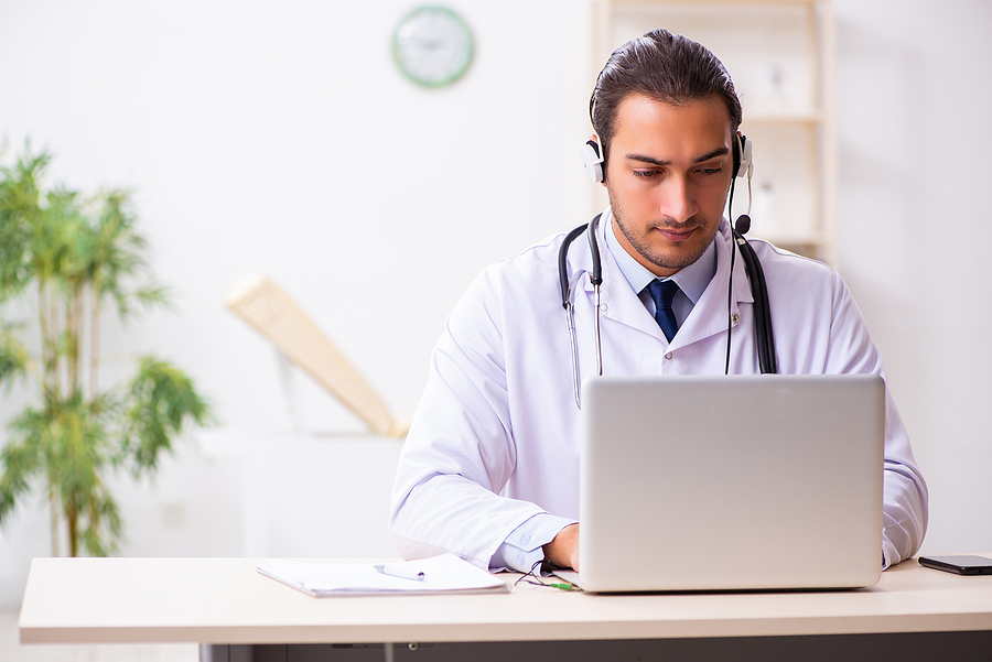 Medical doctor typing on a laptop computer.