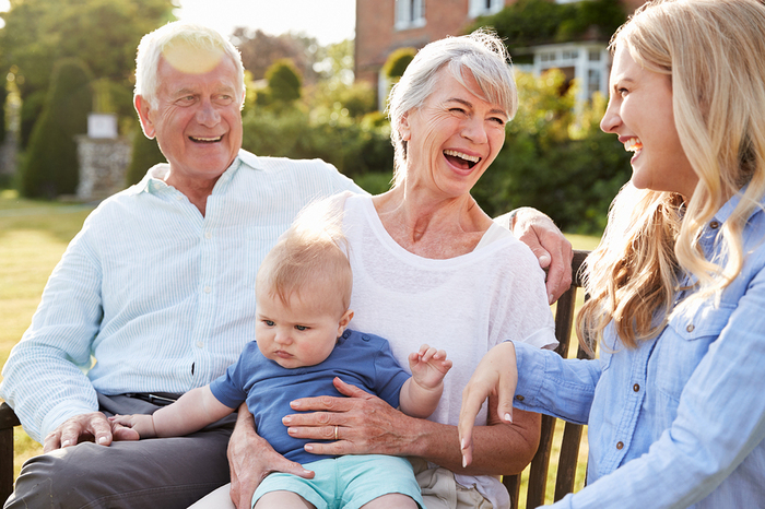 Elderly couple holding a baby smiling.