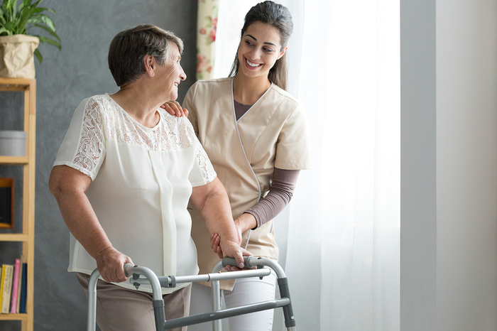 Woman helping an elderly woman with a walker.