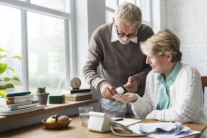 Older couple sitting at a table with blood pressure monitor.