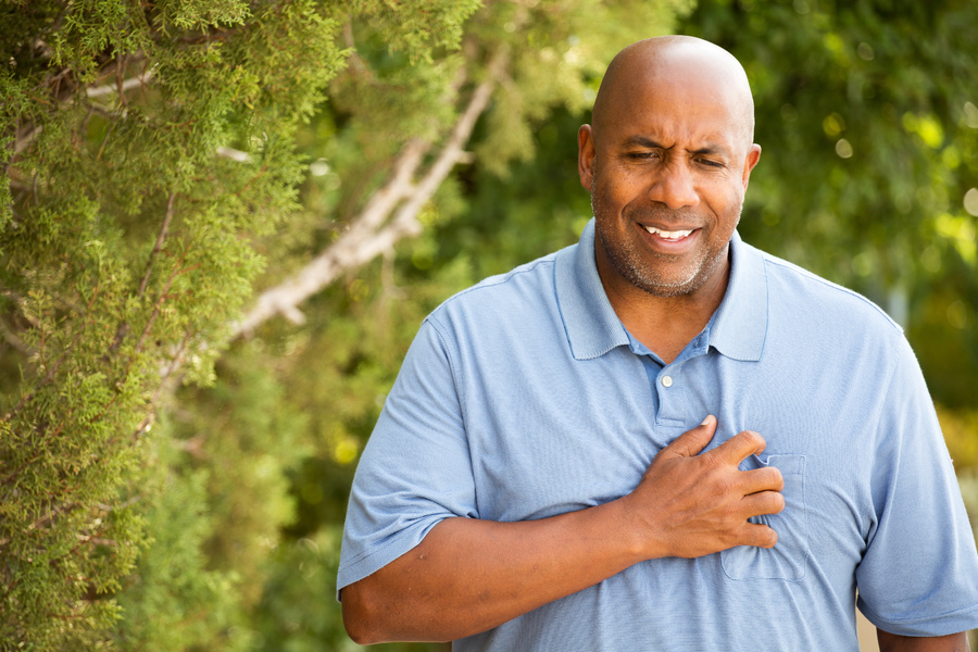 Man holding his hand over his heart appearing in pain.