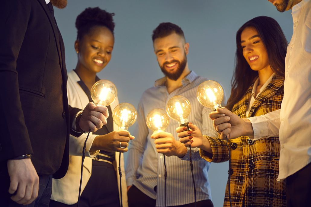 Group holding lit lightbulbs.