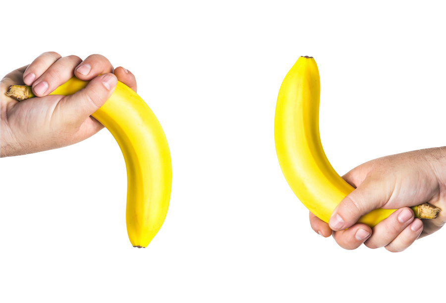 Holding a banana in each hand.