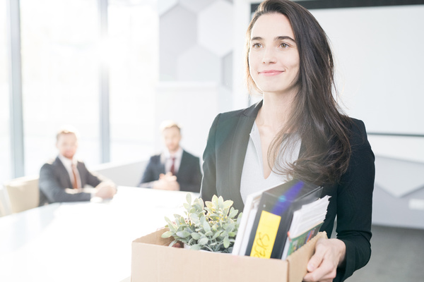 Smiling woman holding a box of items.