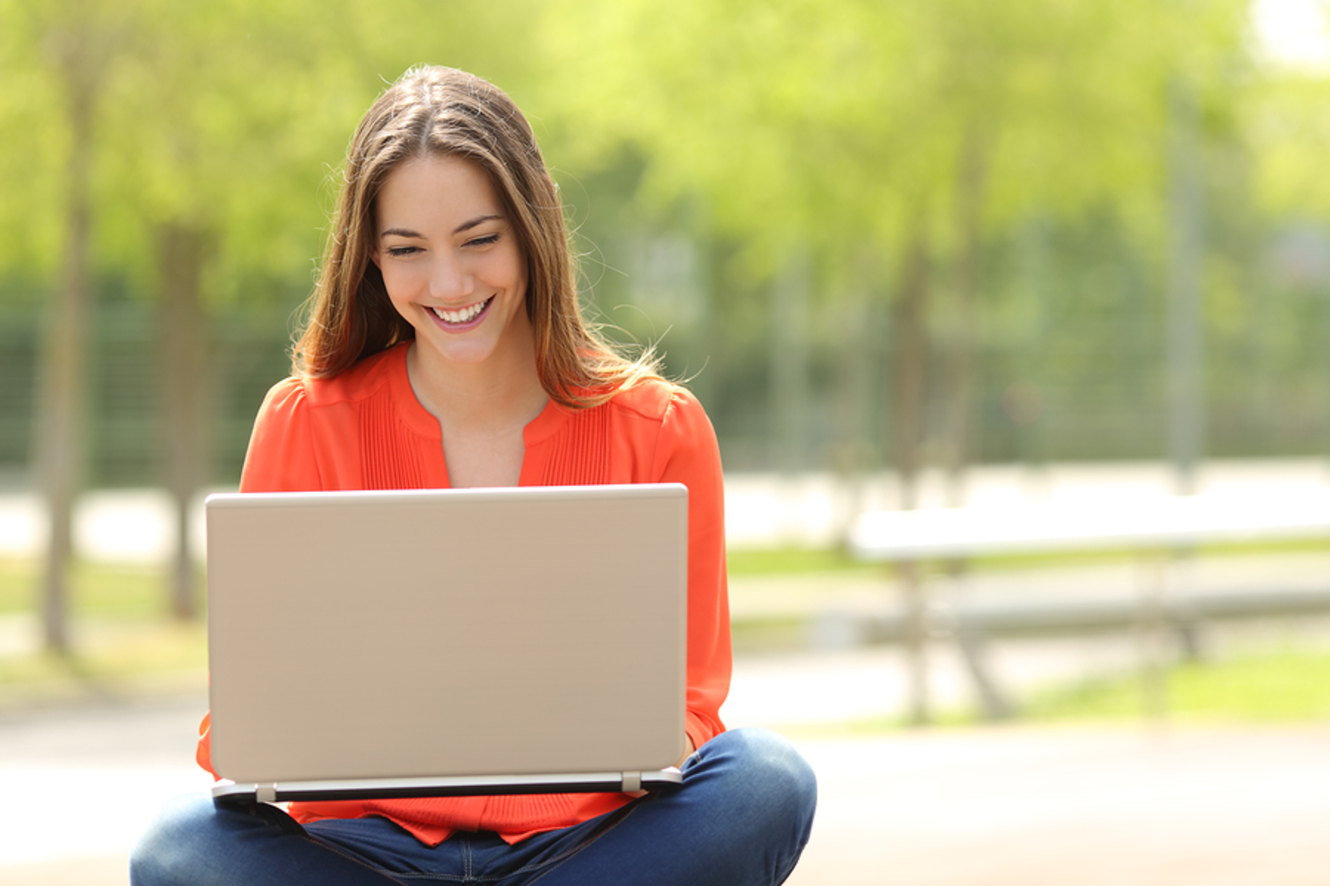 Woman sitting outside using a laptop.