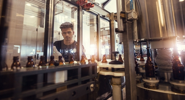 Man observing the manufacturing of liquids in bottles.
