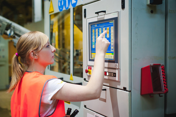 Woman programming a factory machine.