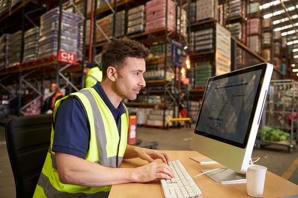 Warehouse employee typing on a desktop computer.
