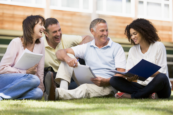 Group of colleagues sitting outside on the grass discussing ideas.