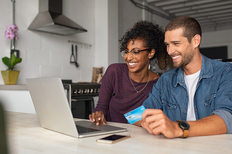 Smiling couple making an online purchase using a credit card.