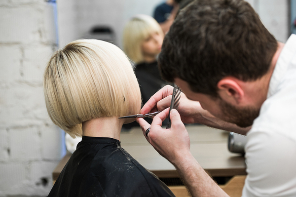 Woman having her hair styled by a male hair stylist.