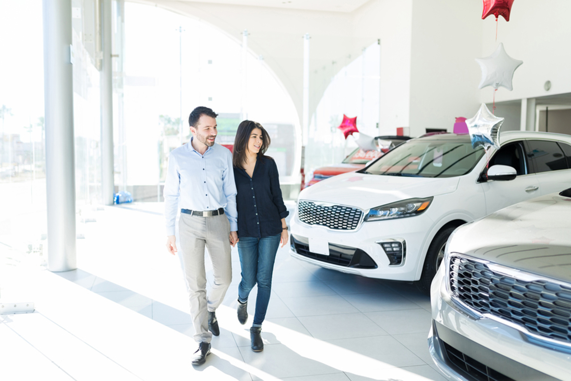 Young couple walking through a car dealership.