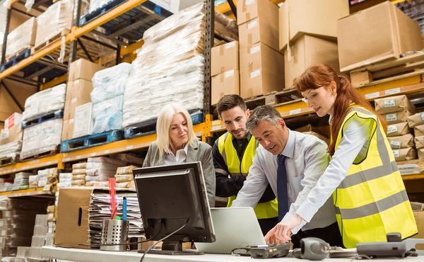 Warehouse workers looking at a laptop computer together.