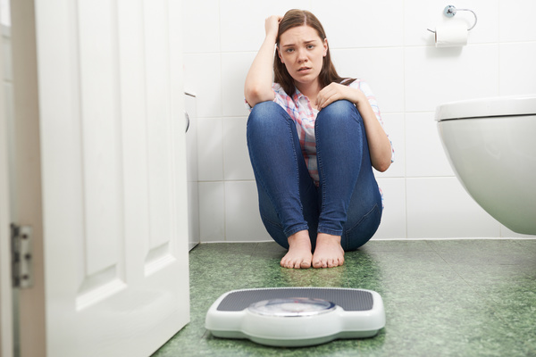 Teen appearing upset on a bathroom floor.