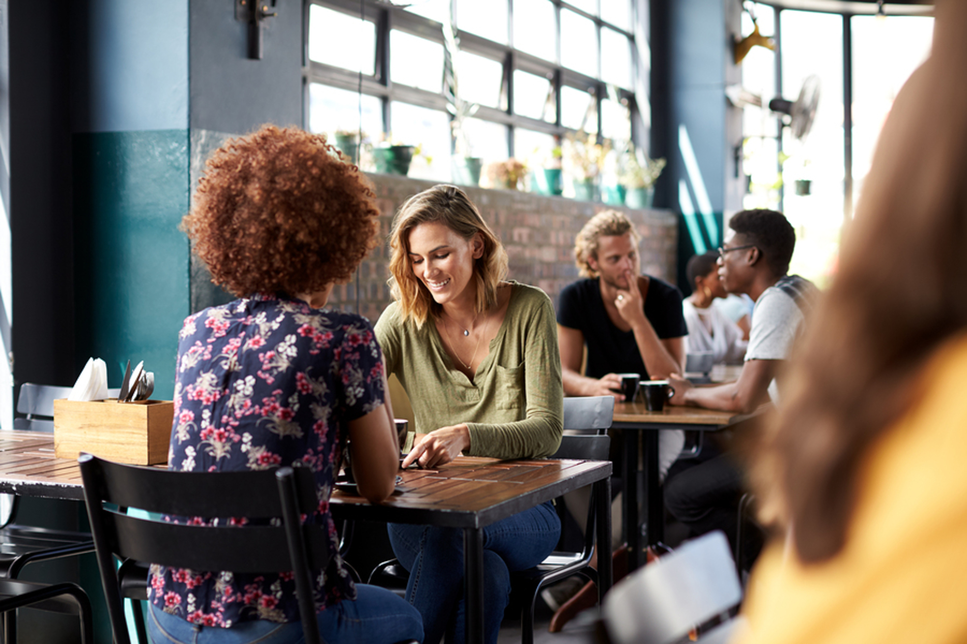 Cafe filled with customers sitting at tables talking.