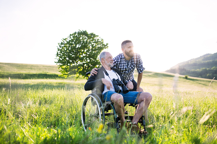 Older man in a wheelchair in a green field.