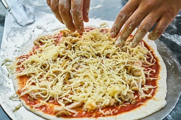 Person creating a pizza.