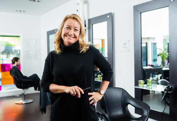 Hair stylist dressed in black smiling.