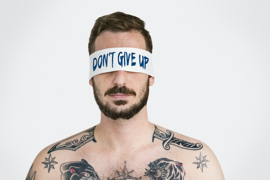 Man with a sign don't give up over his eyes.