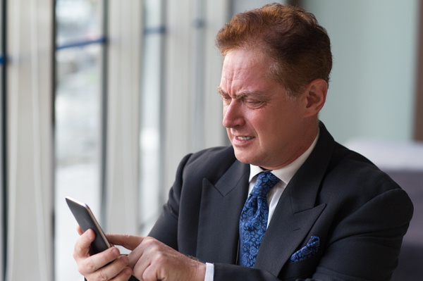 Confused businessman looking at his phone.