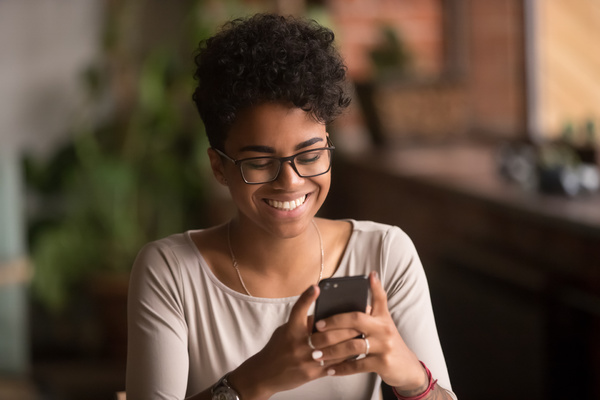 Smiling woman using her phone to SMS.