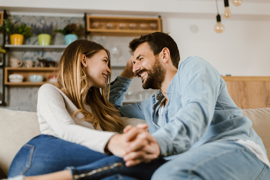 Couple sitting on a couch together having a discussion.