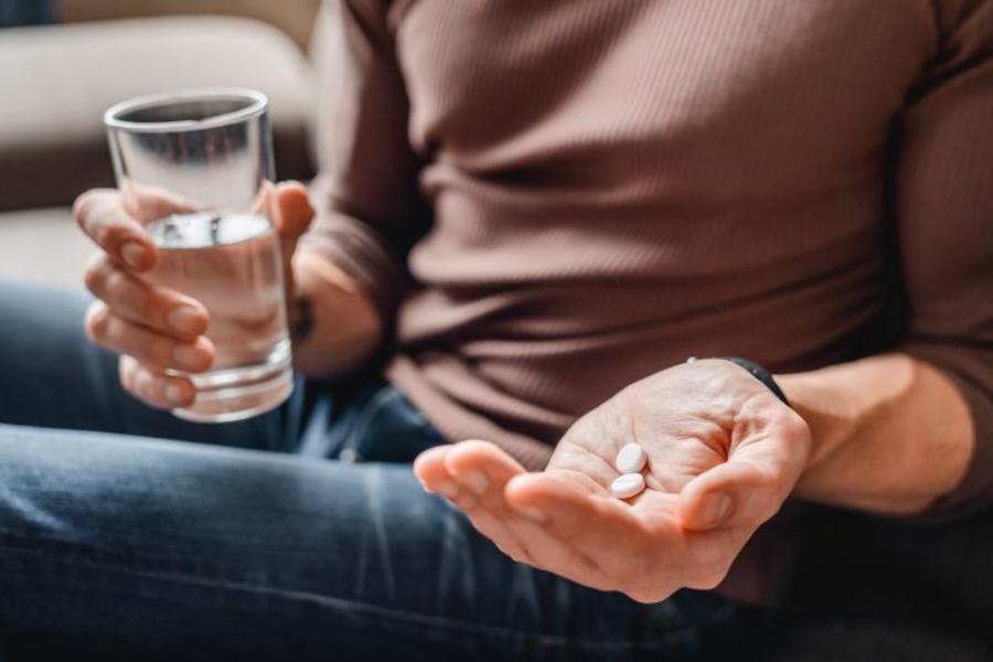 Taking antibiotic pills with a glass of water.
