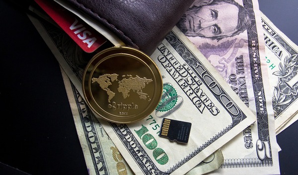 Paper money, a leather wallet and a gold coin with the ripple logo.